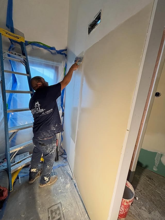 Triple A Construction crew member finishing drywall to a smooth, paint-ready surface